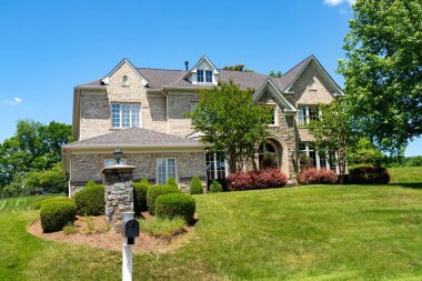 Banliyödeki büyük taş ev. Kuzey Amerika 'da yaz. Güzel manzaralı, çimleri biçilmiş lüks bir ev..