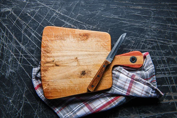 石材深色底座上有刀片和餐巾纸的木制切割板 — 图库照片