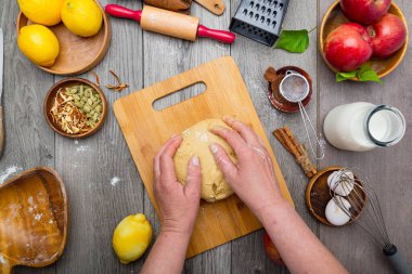 Şefin elleri ve elmalı turta için hazır hamur malzemeleri ile çevrili masada. Yukarıdan görüntüle.