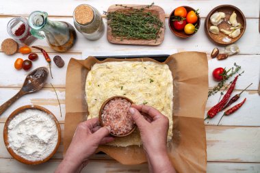 Odaklanarak hazırlanan bir masanın üst görüntüsü. Aşçının elleri, hamur ve malzemelerle birlikte pişirme örtüsü..