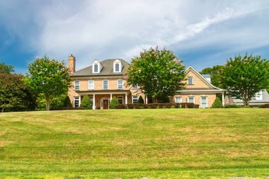 Mavi bulutların altındaki tepedeki taşralı tuğla ev..
