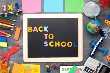 Okul yönetim kurulundaki yazıya geri dönelim. Kalemler, karın ve kırtasiye kağıtları gri arka planda. Yukarıdan görüntüle.