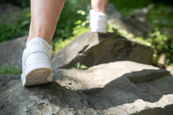 Белый Nike на ногах туриста, лазающего по скалам. Выборочный фокус, вид сзади.