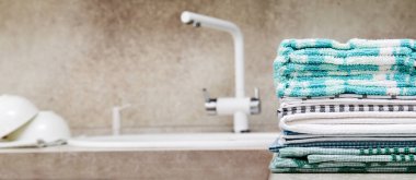 Lavabonun yanındaki mutfak masasında renkli havlu yığını. Boşluğu kopyala