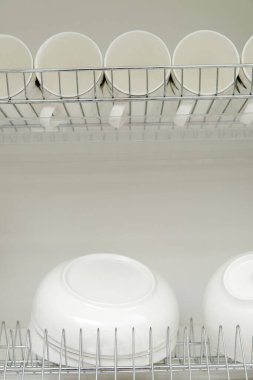 Büyük, beyaz tabaklar ve gözlüklerle kurutmak için metal askı. Geleneksel konforlu mutfak.