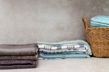 Temiz havlularla dolu bir sepet ve masanın üzerinde bir yığın mutfak havlusu. Boşluğu kopyala.