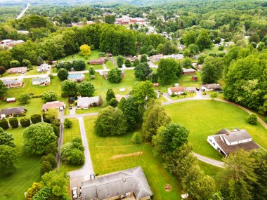 Kırsal yaz manzarası. Yeşilliklerle çevrili evlerin çatıları ve yolları. Bir İHA görüntüsü.