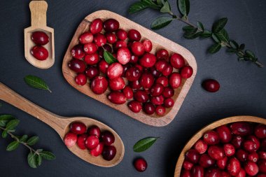 Koyu bir masada kaşıkla ahşap bir kasede olgun kızılcıklar. Yukarıdan görüntüle.