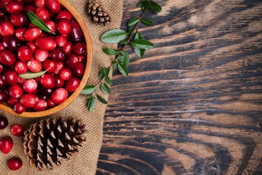 Koyu ahşap masada kaşıkla ahşap bir kasede taze kızılcıklar. Yukarıdan görüntüle. Metin için boşluk.