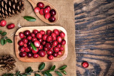 Koyu ahşap masada kaşıkla ahşap bir kasede taze kızılcıklar. Yukarıdan görüntüle. Metin için boşluk.