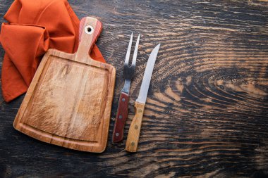 Ahşap kesme tahtası, keten peçete, bıçak ve çatal, ahşap masa üzerinde fotokopi alanı, üst görünüm