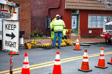 Yol kapanıyor. Verizon işçileri rögar kapağına kablo indiriyor. İnternet hata ayıklaması için Verizon özel ekipmanı