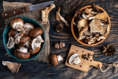 Various dried mushrooms in a wooden bowl and on a cutting board. View from above. clipart