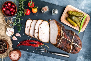 Dilimlenmiş dumanlı ve kaynamış domuz eti ve siyah bir taş tahtada biberiye. Biberli, domatesli ve turşulu. Yukarıdan görüntüle.