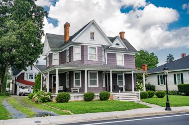 Terası ve ön bahçesinde çimenliği olan iki katlı klasik Amerikan evi..