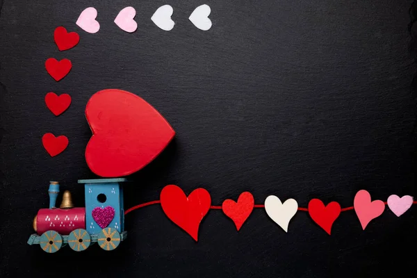 wooden train with tied hearts and a Big Heart on the roof. Cute symbol for celebrating Valentine\'s Day. Copy space.