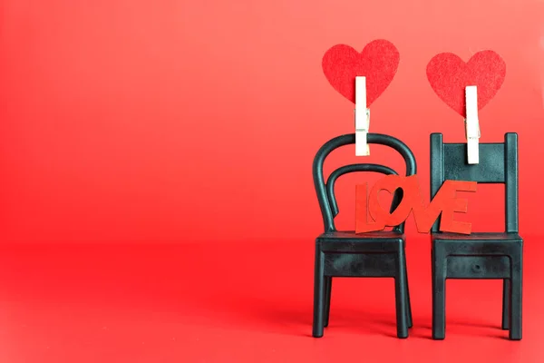 two hearts on two chairs and the word LOVE. Together forever. concept of Valentine\'s Day. Space for text.