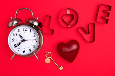 Sevgililer Günü. Kırmızı arka plandaki çalar saat, anahtarı olan bir kalp ve 