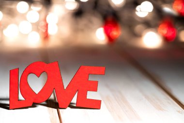 Word LOVE on wooden table against defocused bokeh light background. Love, valentine's day concept. Place for text.