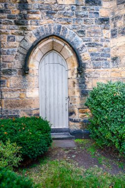 Ön cephe tasarımı. Taş bir duvarın içindeki ahşap ön kapının yakın görüntüsü..