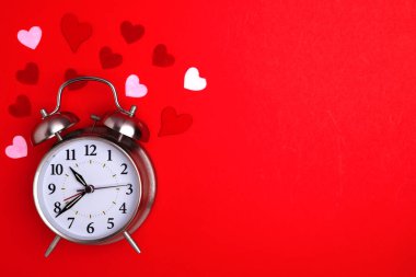 Sevgililer Günü. Kırmızı arka plan ve kalplerdeki çalar saat. Metin için boşluk.