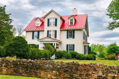 Girişinde çimleri ve çalıları olan geleneksel iki katlı Amerikan evi..
