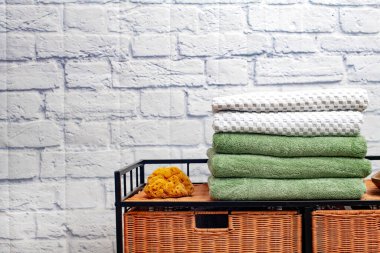 Temiz banyo havlularını banyoda beyaz tuğla arka planda renkli pamuk terry tekstili istifleyin..
