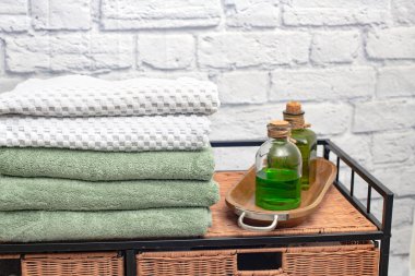 Hasır bir komodinin üzerinde beyaz tuğla bir duvara karşı havlular. Metin için boşluk.