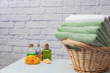 Banyo havluları sepetin içinde beyaz tuğladan bir duvara karşı. Metin için boşluk.
