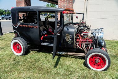 Kaputu açık, motor bölmesinin tepesini gösteren özel siyah bir araba. Vücudunda kafatasları ve farları olan kırmızı tekerlekler ve iskeletler..