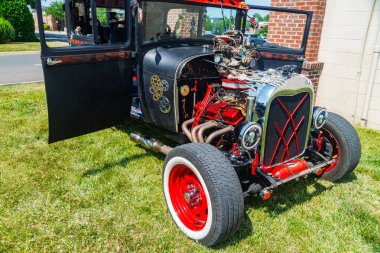 Kaputu açık, motor bölmesinin tepesini gösteren özel siyah bir araba. Vücudunda kafatasları ve farları olan kırmızı tekerlekler ve iskeletler..