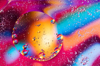 Renkli yağ damlaları kabarcıklar ve küreler. Su yüzeyinde akıyor. Soyut arkaplan. Makro Fotoğraf