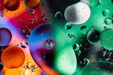 Renkli yağ damlaları kabarcıklar ve küreler. Su yüzeyinde akıyor. Soyut arkaplan. Makro Fotoğraf