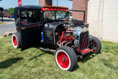 Kaputu açık, motor bölmesinin tepesini gösteren özel siyah bir araba. Vücudunda kafatasları ve farları olan kırmızı tekerlekler ve iskeletler..