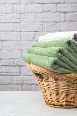 Temiz banyo havluları sepette renkli, pamuk terli tekstil banyoda beyaz tuğla arka planda..