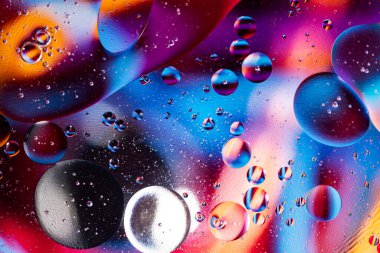 Renkli yağ damlaları kabarcıklar ve küreler. Su yüzeyinde akıyor. Soyut arkaplan Makro Fotoğrafçılık