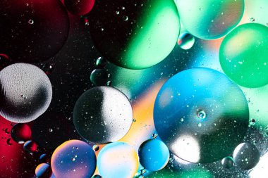 Renkli ışık, su ve yağ damlaları cam üzerine düşer. Işık ve suyun oluşturduğu nefes kesici manzara. Makro fotoğrafçılık. 