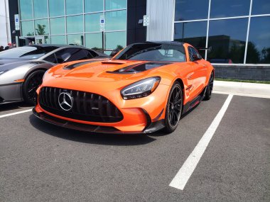 Turuncu Mercedes AMG GT R, Alman spor arabası mağazanın yanındaki otoparkta..