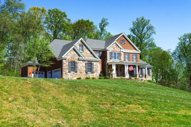 Arka bahçesinde büyük bir çim ve orman olan tuğla kır evi..