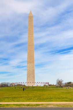 Washington DC 'de açık bir sonbahar gününde insanlar George Washington Anıtı' nın çimlerinde yürür.