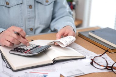Kadınlar, vergi makbuzlarını ödemeden önce hesap makinesinin ev sayımında mali evraklarla çalışırlar. Para biriktirmek için bütçe planlayan kadın