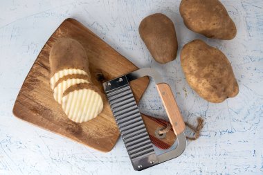 Kıvırcık sebzeler için dalgalı bıçak. Kesme tahtasındaki patates dilimleri. Yukarıdan görüntüle.