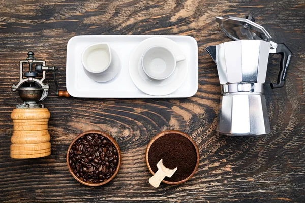 Gayzer kahve makinesi, kahve çekirdeği, kahve öğütücü ve bir kafe için krema. Karanlık masa, üst manzara..