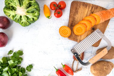 Kıvırcık sebzeler için dalgalı bıçak. Kesme tahtasındaki havuç dilimleri. Soğan, brokoli, domates ve maydanoz manzaralı. Metin için boşluk.