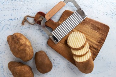 Kıvırcık sebzeler için dalgalı bıçak. Kesme tahtasındaki patates dilimleri. Yukarıdan görüntüle.