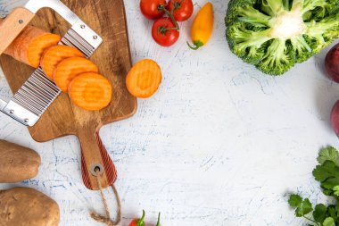 Kıvırcık sebzeler için dalgalı bıçak. Kesme tahtasındaki havuç dilimleri. Soğan, brokoli, domates ve maydanoz manzaralı. Metin için boşluk.