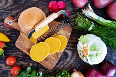 Kesme tahtasında dalga bıçağıyla kesilmiş bir balkabağı. Tahta bir masada çeşitli sebzeler. Yukarıdan görüntüle.