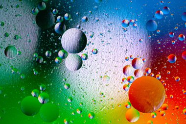 Suda yüzen yağ damlasının renkli bir sanatçısı. Soyut renkler su kabarcıkları arka plan. Bayram ışığı arka planı. Su yüzeyine yağ damlaları