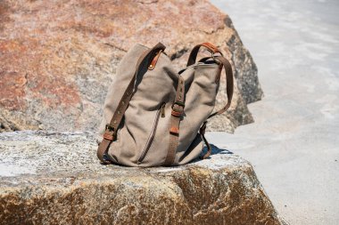 Güneşli bir günde büyük bir kayanın üzerinde bırakılan bez çanta..