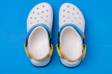 Mavi arka planda kayışlı beyaz timsah terlikleri. Rahat unisex plaj ayakkabıları.